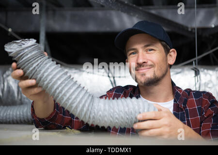 Tecnico di impianti di termoventilazione pronto per installare il sistema di ventilazione in casa Foto Stock