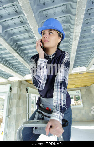 Donna builder sul telefono sulla scaletta Foto Stock