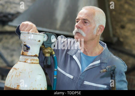 L'uomo chiudere la valvola dei manometri di pressione sul serbatoio di ossigeno Foto Stock