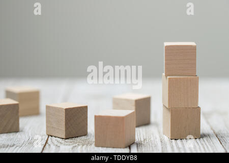 Tre giocattolo di legno i cubi su grigio Sfondo di legno Foto Stock