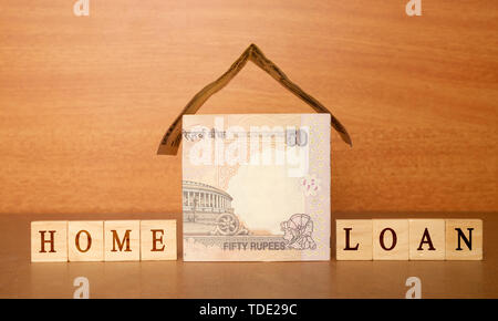 Casa fatta dalla valuta indiana note e Home prestito in blocco di legno lettere sullo sfondo di legno. Foto Stock