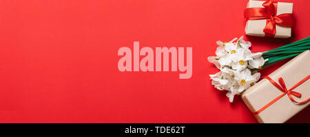 Bianco fresco narcisi fiori con confezione regalo su sfondo rosso per le congratulazioni per le donne, le mamme e le figlie. Foto Stock