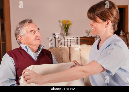 Giovane infermiere avendo cura di senior uomo a casa Foto Stock