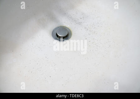 Bianco sporco lavaggio bacino dissipatore che mostra una schifezza svuotare con le punte dei capelli. Il tappo è un brutto sporco disgustoso lordo chrome in acciaio inox della materia Foto Stock