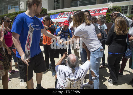 San Diego, CA, Stati Uniti d'America. Il 15 giugno, 2019. Un unidentified Trump sostenitore, centro sorge su Frank Kullen, un Vietnam-era il veterano dell'esercito che hanno cercato di swat una fotocamera fuori della sua mano durante una manifestazione svoltasi a mezzogiorno a San Diego Federal Courthouse. Un altro Trump sostenitore poi lo ha colpito a terra. Credito: ZUMA Press, Inc./Alamy Live News Foto Stock