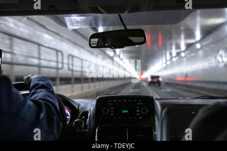 Lincoln Tunnel, New York. Taxi maschio cab driver tiene il volante. Vista ravvicinata sul cruscotto Foto Stock