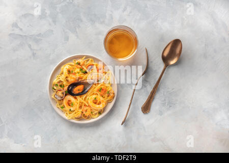 Piatti di pasta. Tagliolini con cozze, gamberi, vongole e anelli di totano, girato da sopra con un bicchiere di vino bianco e un posto per il testo Foto Stock