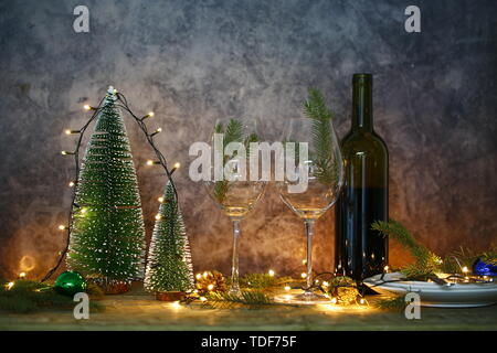 Vino rosso sul tavolo con albero di Natale. Tavolo da pranzo e luci di Natale. Foto Stock