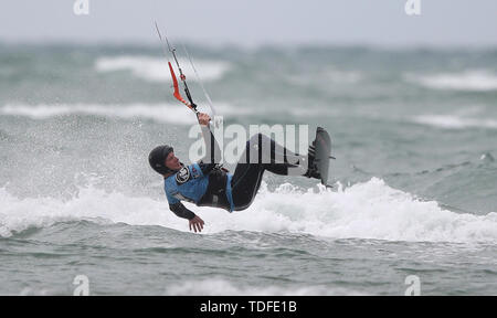 Un kite surfer sfrutta i forti venti che saltano fuori del mare al largo di West Wittering beach in West Sussex. Foto Stock