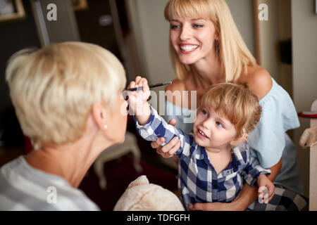 Bambino Piccolo che abbellisce il suo grand mom con il trucco in camera Foto Stock