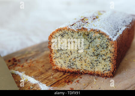 Torta con semi di papavero e la scorza di limone, spolverati con zucchero a velo. Tortina al limone su una tavola di legno Foto Stock