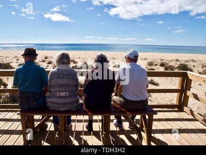 Gli anziani sono seduti su una panchina a guardare la spiaggia Foto Stock