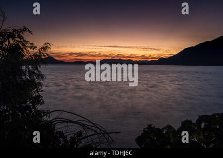 Cameron Lago sull'Isola di Vancouver, Canada al tramonto, il cielo incandescente rosa e viola come il vento crea increspature sul lago, nessuno nell'immagine Foto Stock