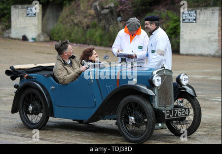 Il Marshalls da VSCC (Vintage Sports Car Club) chat per il conducente di un 1932 Austin sette freccia sport, come essi si impegnano una prova di azionamento durante la Brooklands Double dodici Motorsport Festival a Brooklands Museum, Weybridge, Surrey. Foto Stock