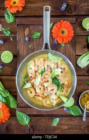 Zuppa di gamberi al curry servita in una pentola d'argento su un tavolo marrone Foto Stock