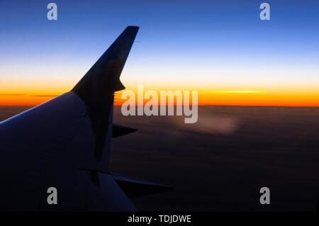 La vista dalla finestra di un jet privato come il sole tramonta sull'orizzonte Foto Stock