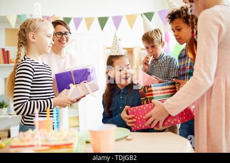 Ritratto di felice ragazza adolescente ricevere doni circondato da amici durante la festa di compleanno, spazio di copia Foto Stock