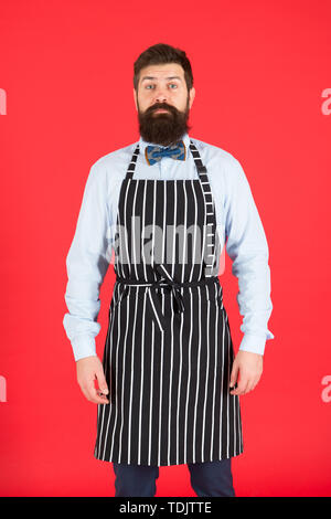 Io sono totalmente a vostro servizio. Un uomo servo. Uomo Barbuto che indossa la bib grembiule. L'uomo cook con barba e baffi in cucina il grembiule. Elegante uomo cameriere o barista. Foto Stock