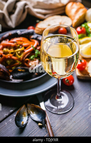 Un bicchiere di vino bianco secco sullo sfondo della cucina italiana. Pasta, cozze e vino. Foto Stock