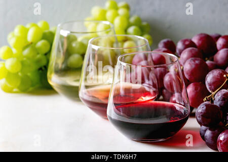 Varietà di vino. Rosso, rosa e vino bianco in Old fashion occhiali con grappoli di uva bianca sulla tavola di marmo Foto Stock