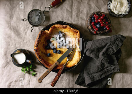 Freschi di forno olandese frittella di bambino in ghisa pan servita con blackberry e rosse bacche Ribes, il mascarpone, lo zucchero in polvere, brocca di crema, vintage Foto Stock