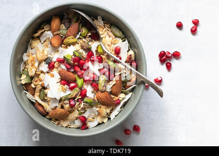 Ciotola di muesli e rabboccato con mandorle e pistacchi, essiccato di cocco e i semi di melograno. Foto Stock