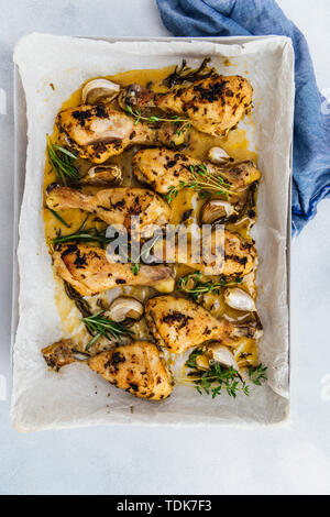 Cotta nel forno le cosce di pollo con erbe e aglio in una teglia da forno fotografata da vista dall'alto. Foto Stock