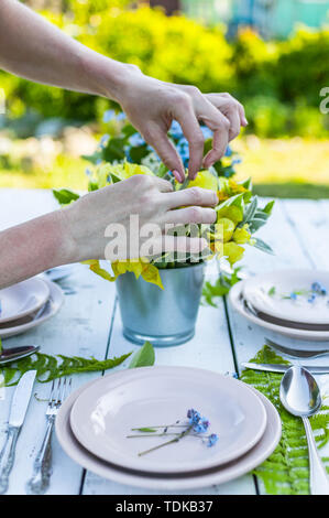 Fioraio rendendo elegante bouquet di dimenticare blu-me-non fiori su un bianco tavolo di legno. Stile rustico decorazione Foto Stock