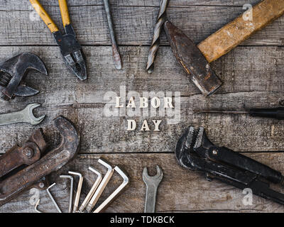 Festa del lavoro. Gli strumenti a mano e lettere in legno giacente sul tavolo. Vista superiore, close-up. Preparazione per la celebrazione. Congratulazioni ai cari, famiglia, Foto Stock