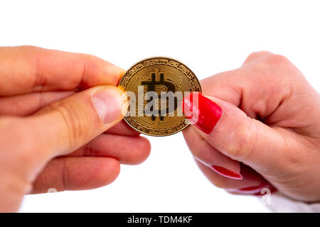 Virtual cryptocurrency denaro Bitcoin medaglia d oro nelle mani di una donna con il rosso smalto per unghie e un uomo. Il futuro di denaro. Isolato su un retro bianco Foto Stock