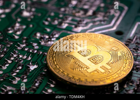 Virtual cryptocurrency denaro Bitcoin medaglia d'oro su un calcolatore verde scheda a circuito stampato PCB. Il futuro di denaro. Apparecchiature di calcolo. Ima scuro Foto Stock