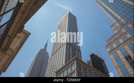 New York Manhattan centro commerciale. Grattacieli e Empire State building in prospettiva contro il cielo blu, sfondo a basso angolo di visione, molla sunn Foto Stock