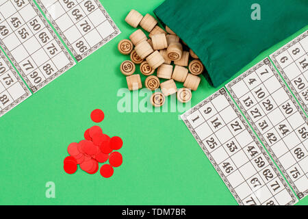 Lotto in legno Barili con borsa di stoffa, gioco di carte e chip rossi su sfondo verde. Gioco di bordo del lotto. Vista dall'alto. Foto Stock