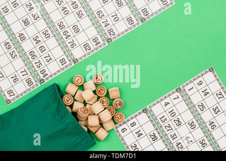 Lotto in legno Barili con borsa di stoffa e carte da gioco su sfondo verde. Gioco di bordo del lotto. Vista da sopra con copia spazio. Foto Stock