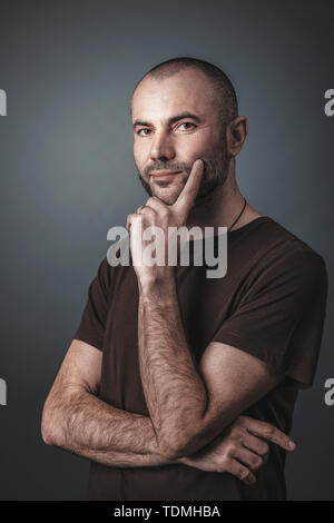 Ritratto di uomo caucasico con barba corta e testa, espressione pensosa. Foto Stock