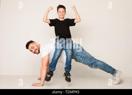 Papà facendo spingere ups con figlio sul retro Foto Stock