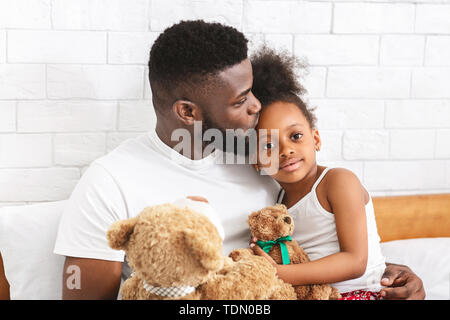La cura di papà africano baciando la sua adorabile figlia piccola in fronte Foto Stock