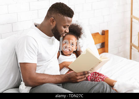 African American uomo la lettura di fiaba per la sua piccola figlia Foto Stock
