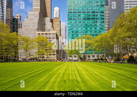 New York, Manhattan Skyline vista dal Bryant Park, primavera. Grattacieli, persone rilassante, prato verde e alberi, cielo blu chiaro sfondo Foto Stock