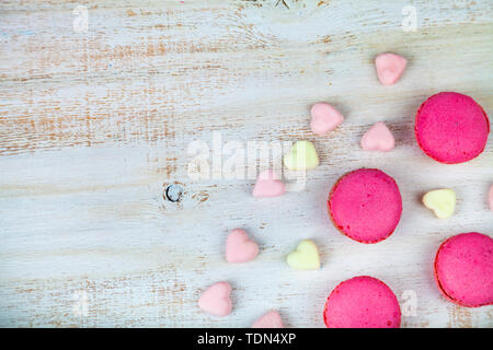 Fragola macarons e marshmallows su uno sfondo di legno. Foto Stock