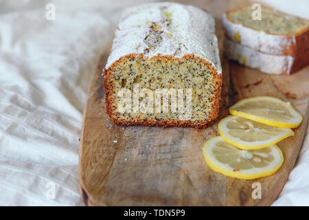 Torta con semi di papavero e la scorza di limone, spolverati con zucchero a velo. Tortina al limone su una tavola di legno Foto Stock