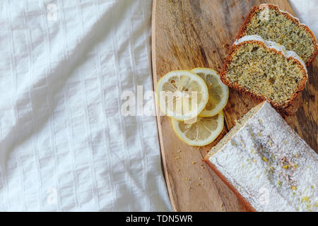 Torta con semi di papavero e la scorza di limone, spolverati con zucchero a velo. Tortina al limone su una tavola di legno Foto Stock