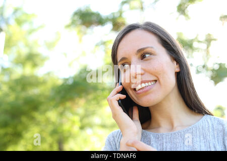 Donna felice colloqui su smart phone in piedi all'aperto in un parco Foto Stock