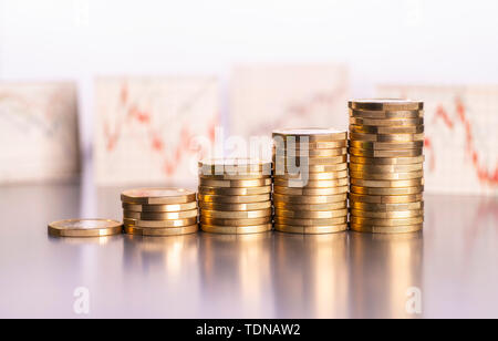 Aumento di pile di monete e i grafici con i prezzi azionari in background Foto Stock