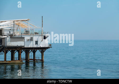 Piattaforma su supporti in mare vicino alla riva. Giorno chiaro e blu cielo sopra il mare. Foto Stock