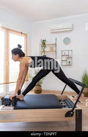 Giovane donna esercita sul pilates reformer bed Foto Stock