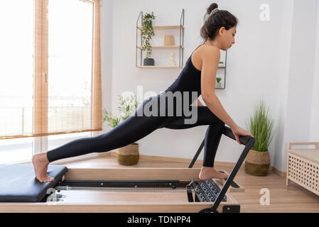 Giovane donna esercita sul pilates reformer bed Foto Stock