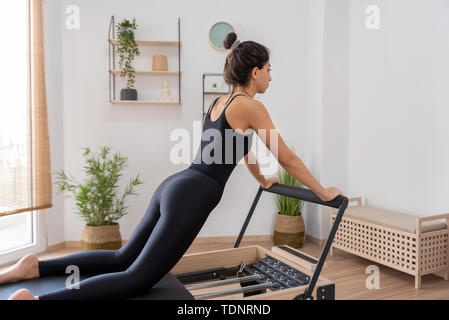 Giovane donna esercita sul pilates reformer bed Foto Stock