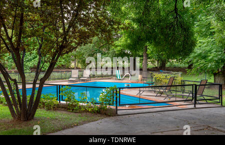 Piscina blu, verdi alberi, un recinto e confortevoli sedie Foto Stock