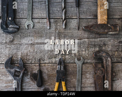 Festa del lavoro. Gli strumenti a mano e lettere in legno giacente sul tavolo. Vista superiore, close-up. Preparazione per la celebrazione. Congratulazioni ai cari, famiglia, Foto Stock